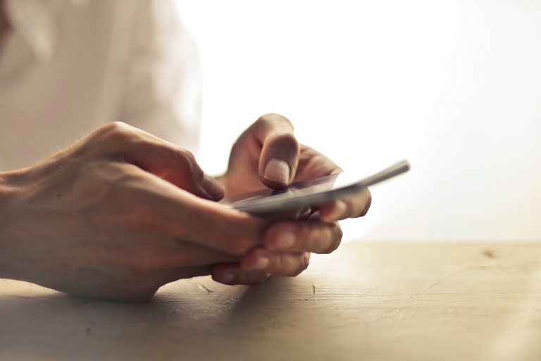 A close up of someone typing on a smartphone in warm lighting