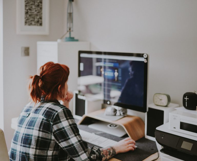 A redhaired woman looks at her computer