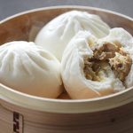 Pork steam buns sit in a bamboo steamer
